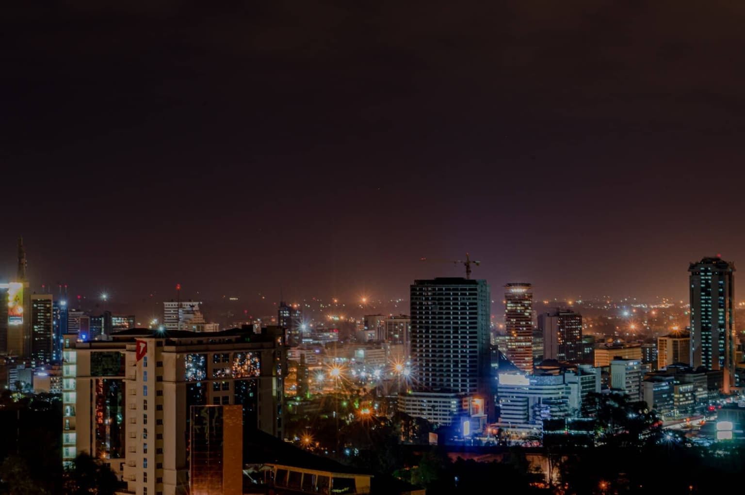 The Nairobi skyline lit up at night under a dark sky.